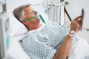 a man, in a hospital bed, wearing an oxygen mask to breathe. Pulmonary embolism